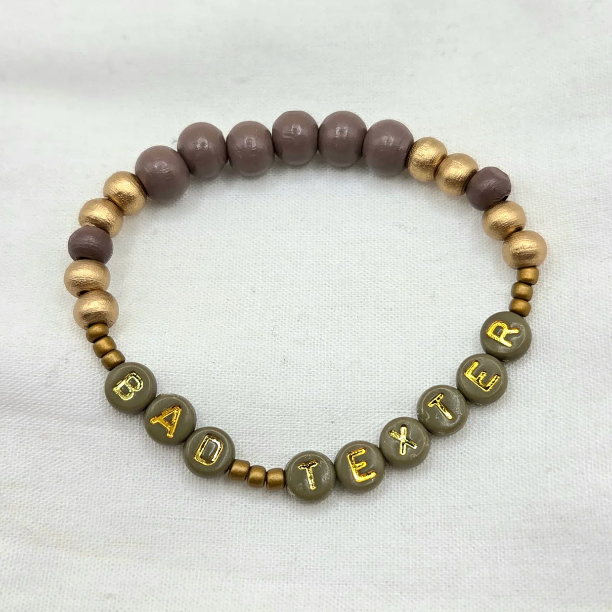 Handmade beaded bracelet with 'BAD TEXTER' in gold letters, earthy tones, cozy gift idea