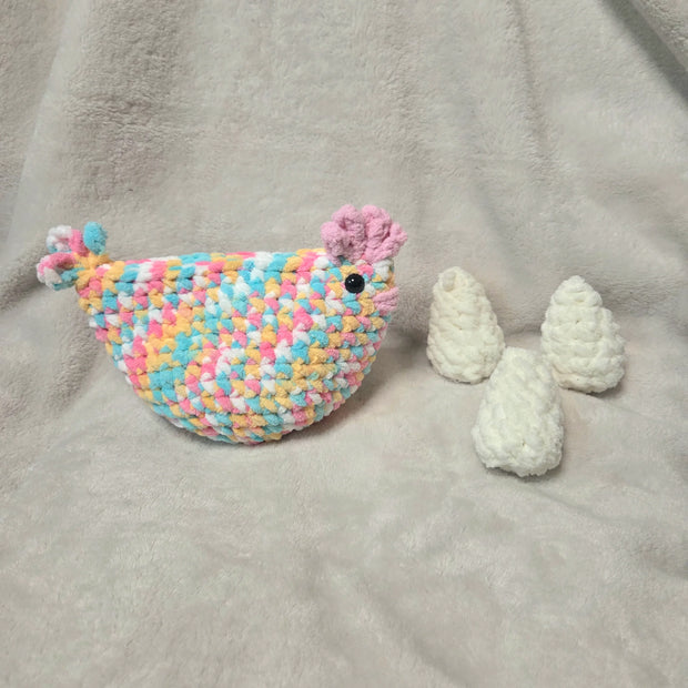 Colorful crocheted chicken with eggs on soft blanket