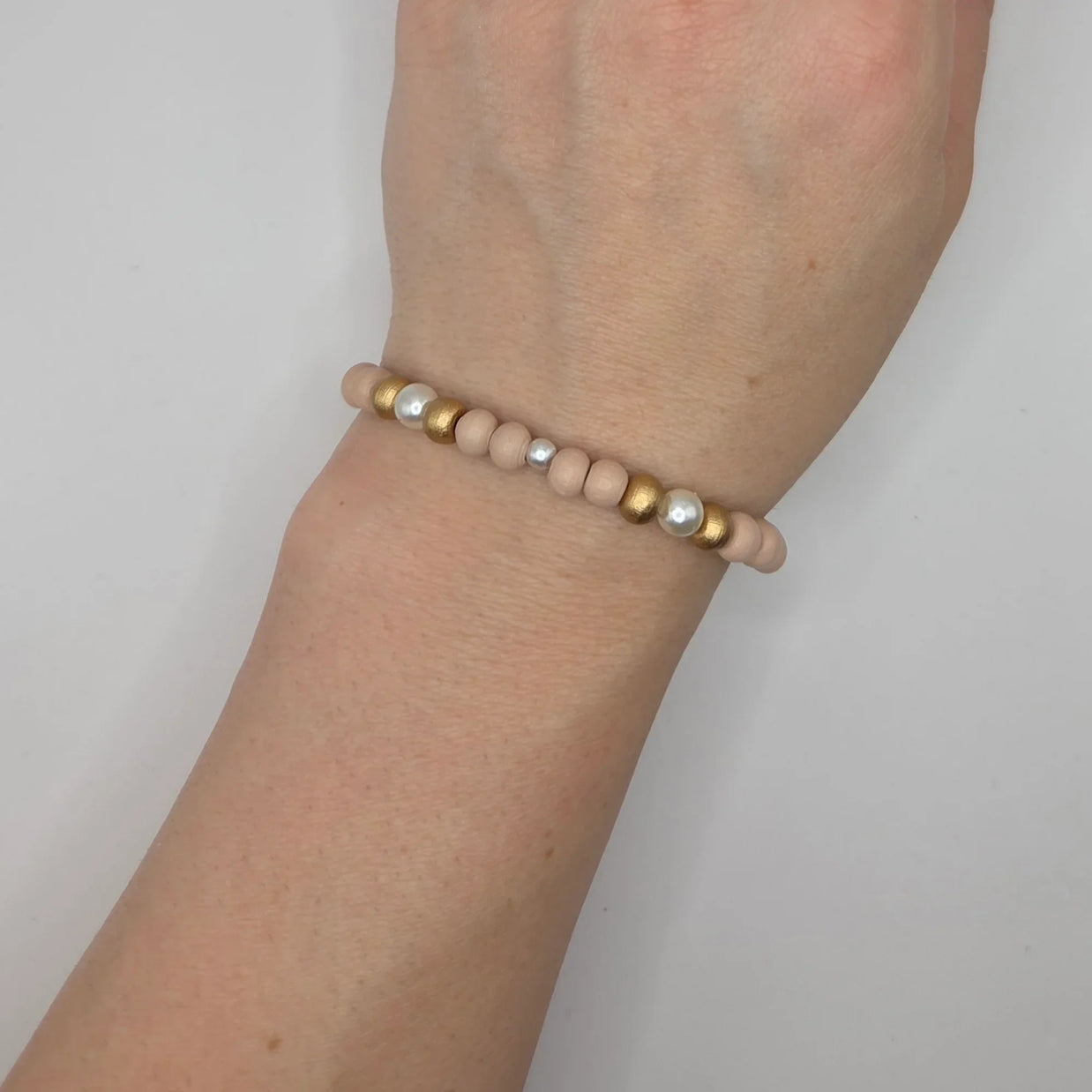 Handmade beaded bracelet with blush wood, gold, and pearl beads on wrist